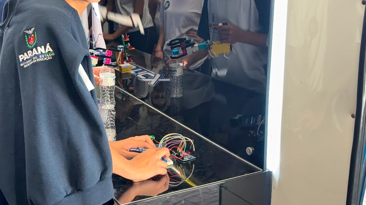 Aluno com uniforme da rede estadual do Paraná montando um circuito eletrônico