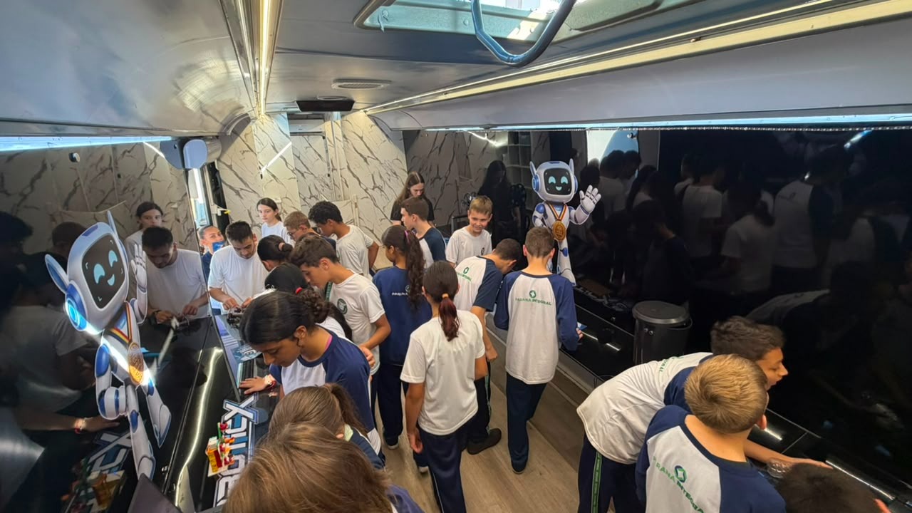 Estudantes uniformizados participando de uma aula dentro do ônibus RoboticX